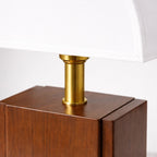 Närbild på bordslampa med vit skärm, guldfärgad detalj och träbas som visar material och finish i hög kvalitet