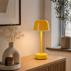 Gul uppladdningsbar bordslampa Domo på träsideboard med modern nordisk inredning och varm belysning.