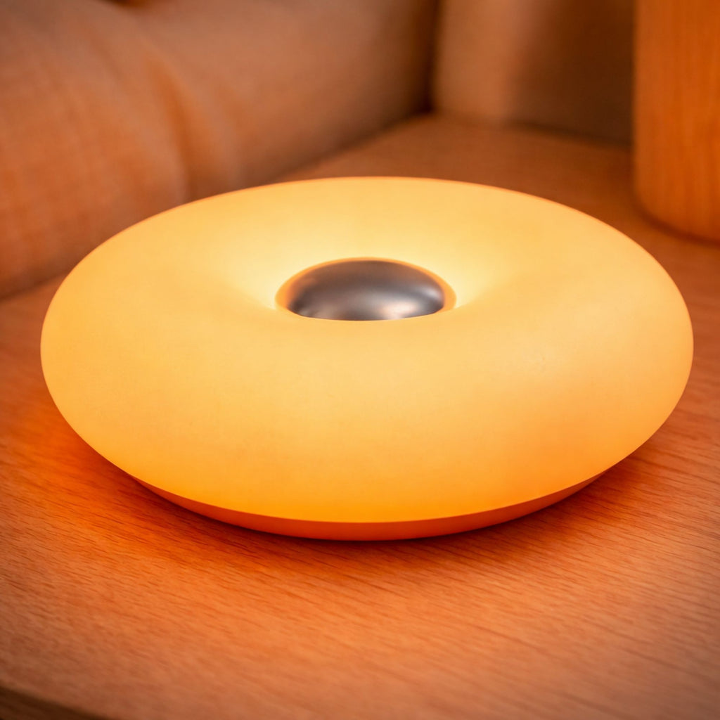 Närbild på orange uppladdningsbar portabel LED bordslampa i vit donut-design med mjukt dimbart ljus