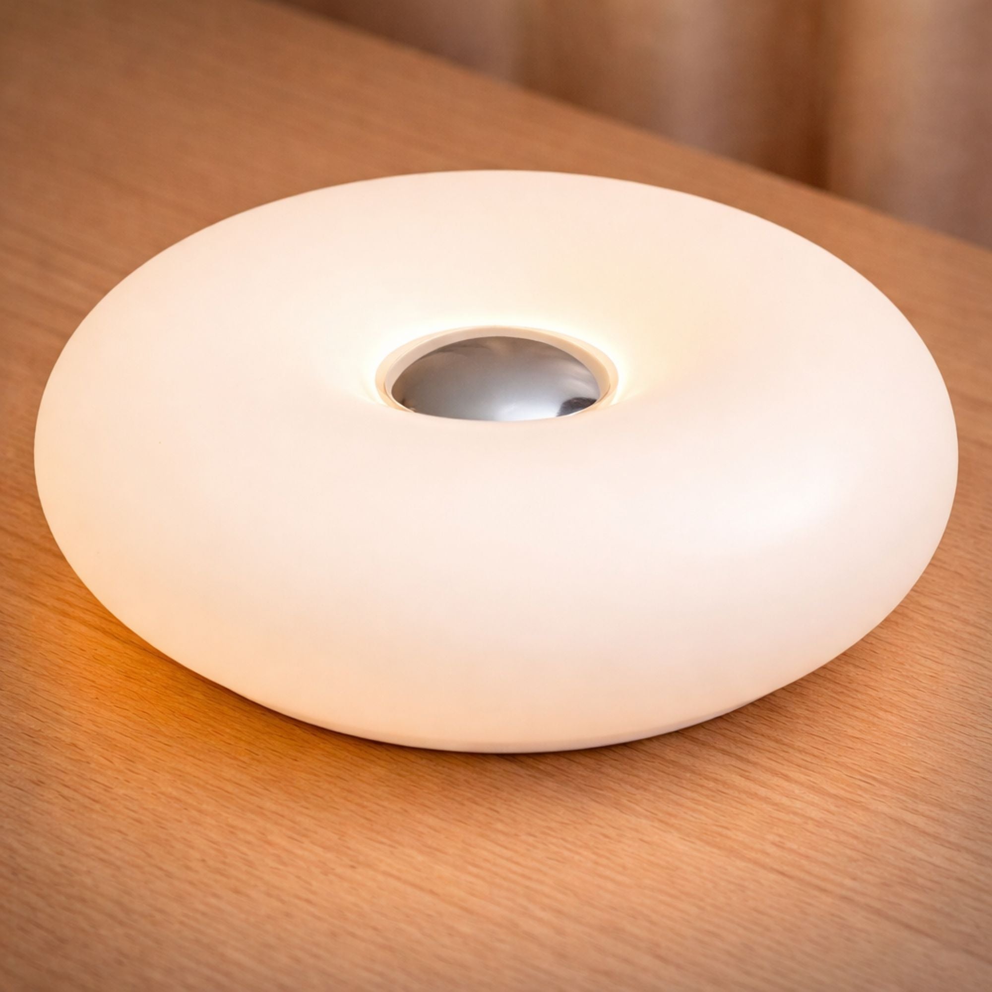 Närbild på vit uppladdningsbar portabel LED bordslampa i vit donut-design med mjukt dimbart ljus