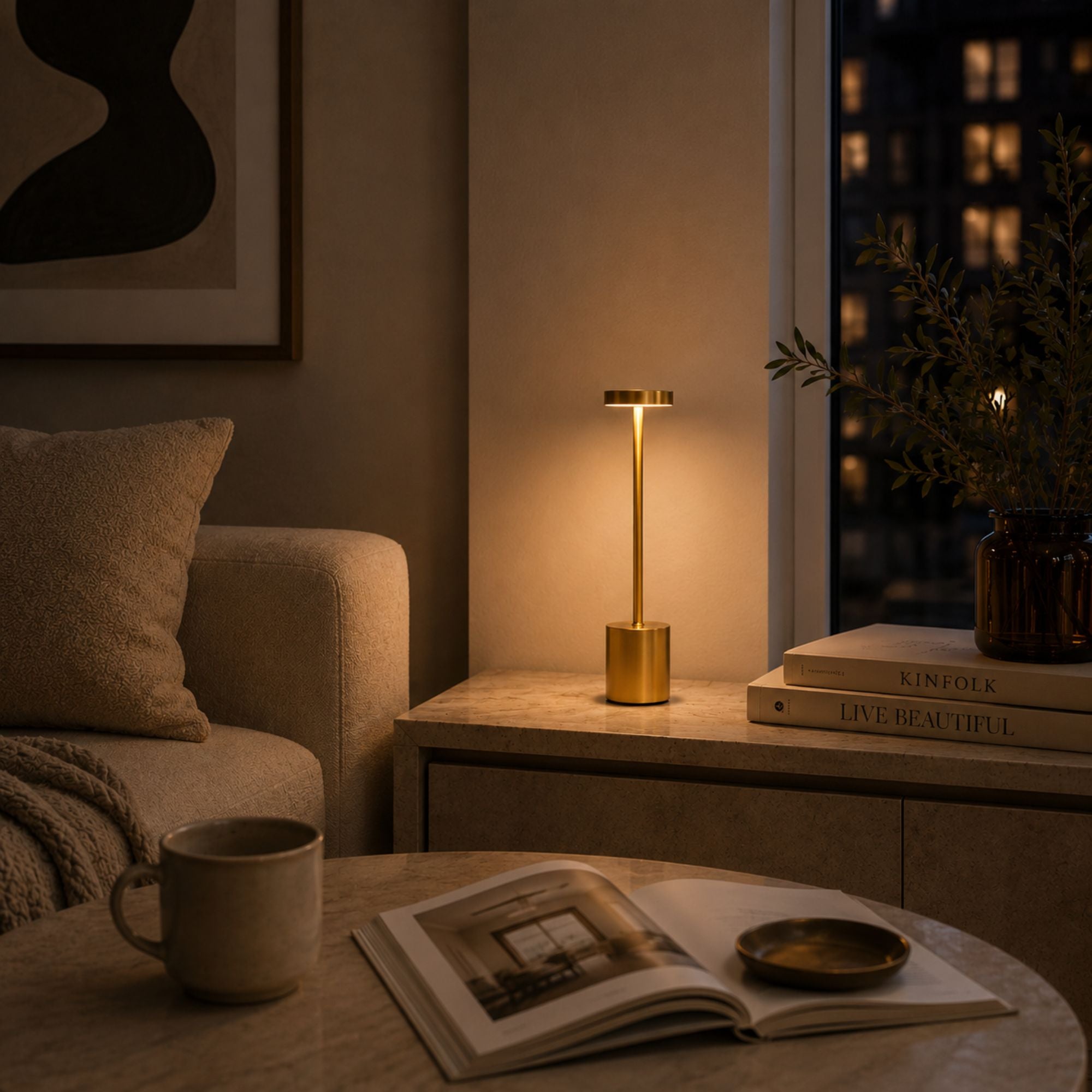 Guldig uppladdningsbar LED-bordslampa i ett skandinaviskt vardagsrum med varm kvällsbelysning, böcker och modern minimalistisk inredning.