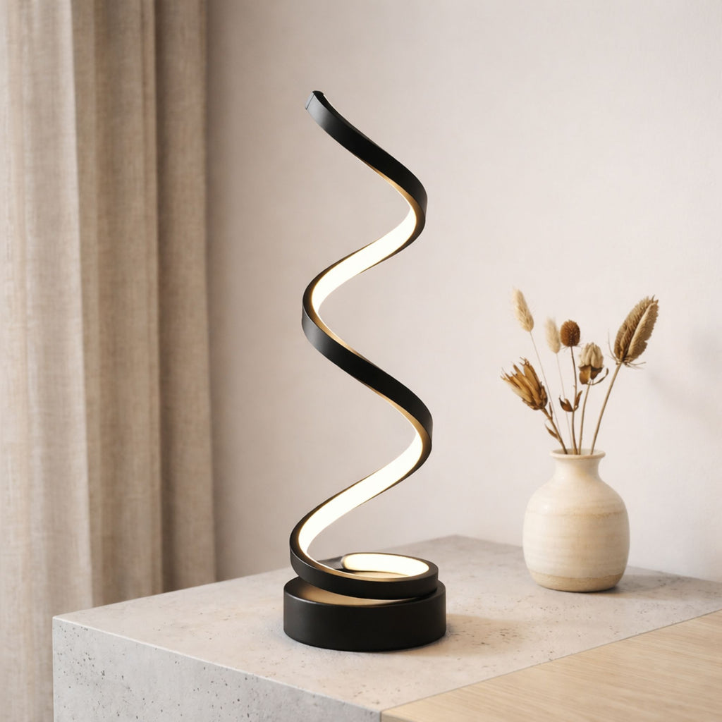 Bordslampa i svart modern design med slingrande LED-belysning på bord.