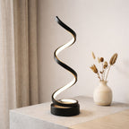 Bordslampa i svart modern design med slingrande LED-belysning på bord.