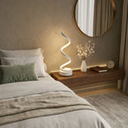 Bordslampa i modern vit design med LED-belysning placerad på nattduksbord i sovrum.