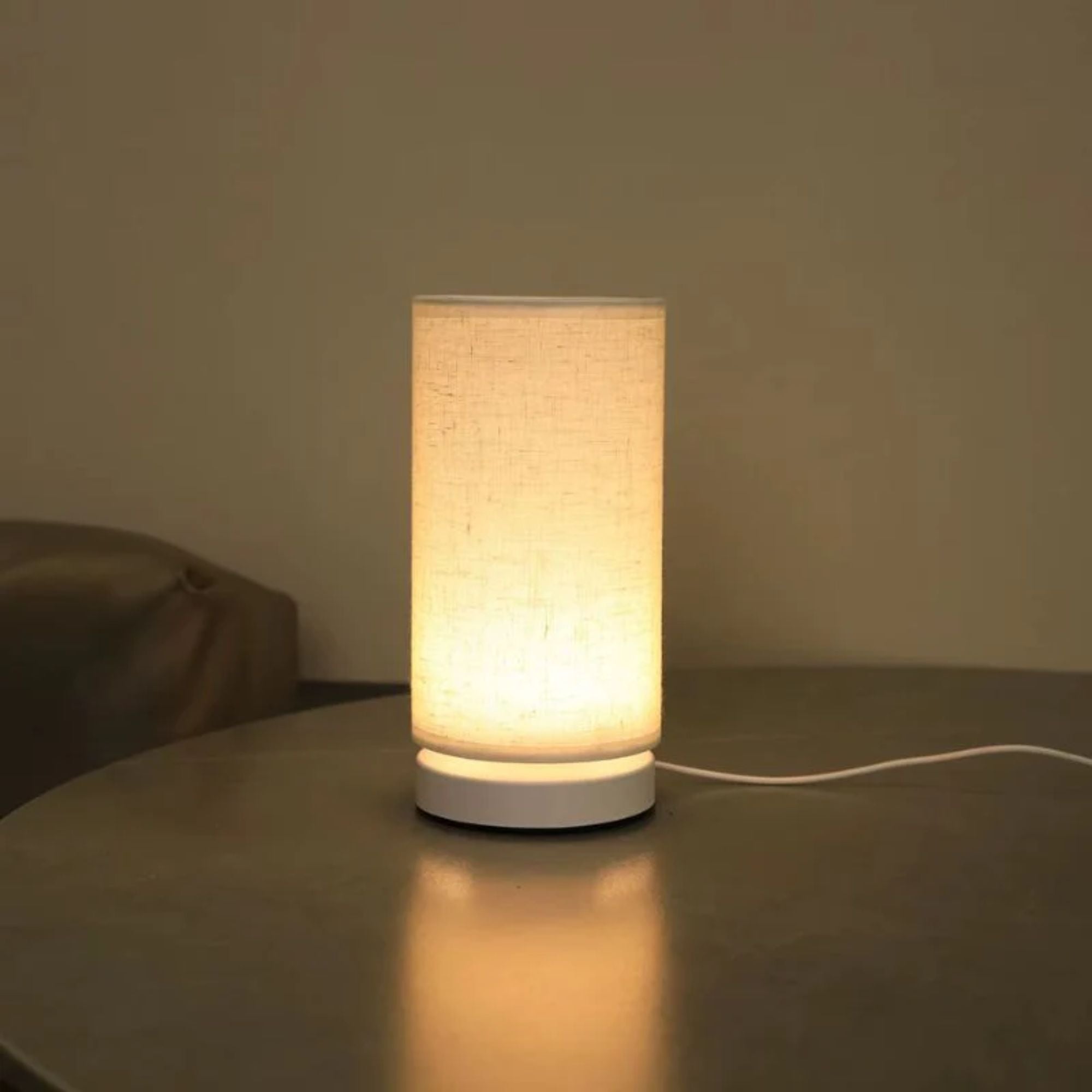 LED bordslampa med varm belysning på bord i mörk miljö som skapar mysig kvällskänsla.