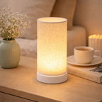 Bordslampa med varm LED-belysning placerad på sängbord som skapar mysig atmosfär i vardagsrum.