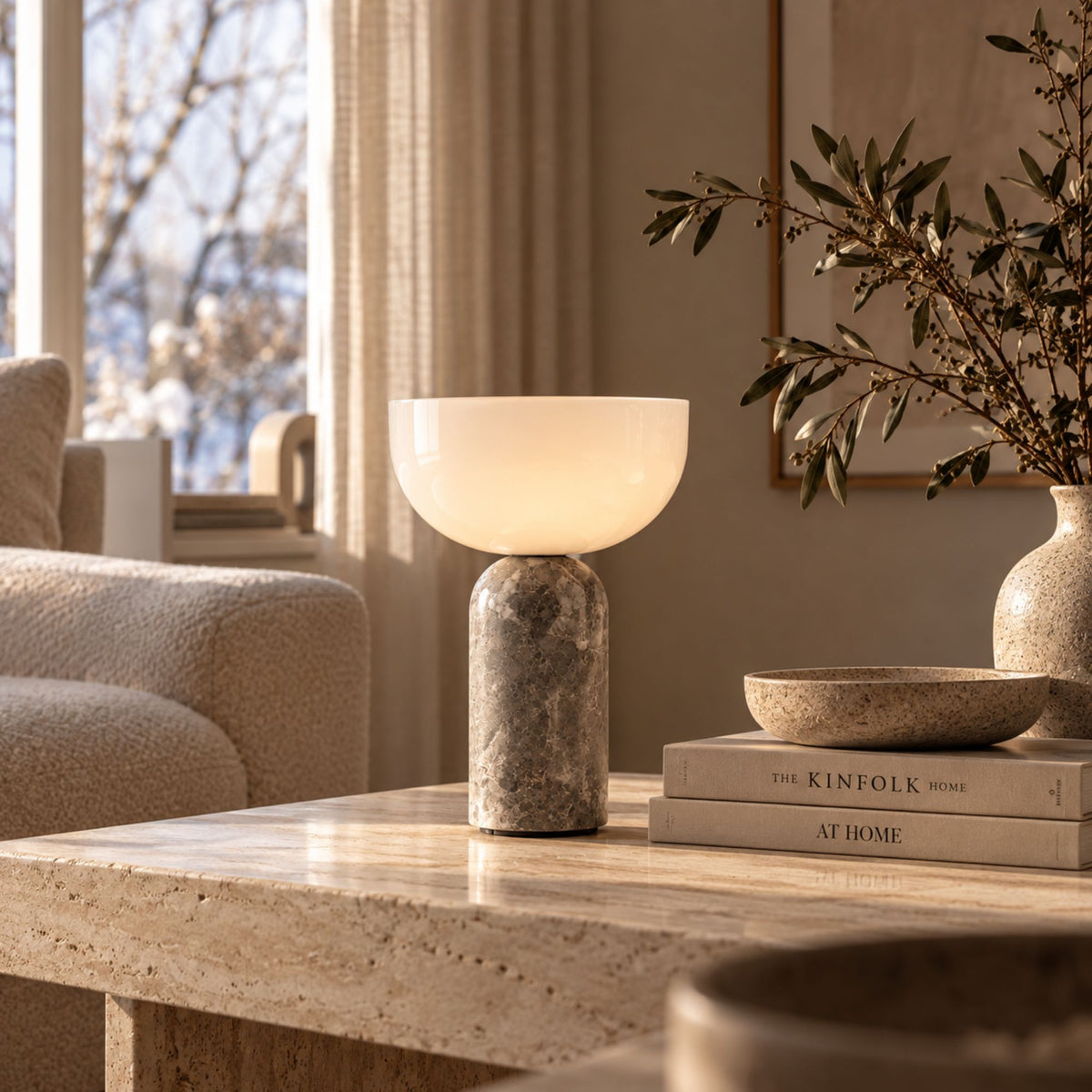 Bordslampa i grå marmor med varm belysning på soffbord i vardagsrum.