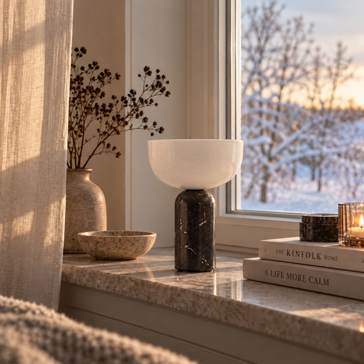 Svart bordslampa i marmor med vit skärm på en fönsterbänk.