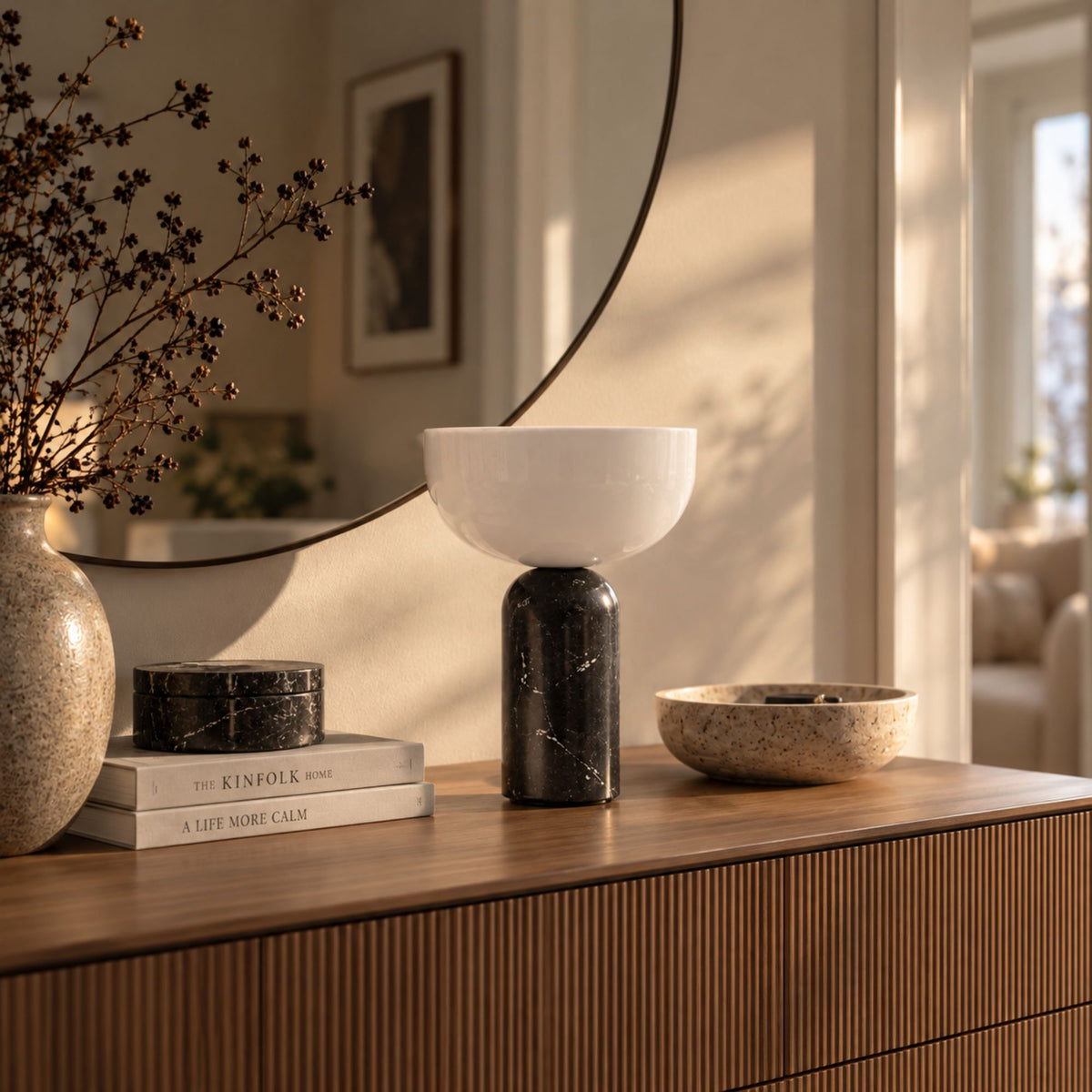 Bordslampa KINZO i svart marmor på sideboard under en rund spegel.