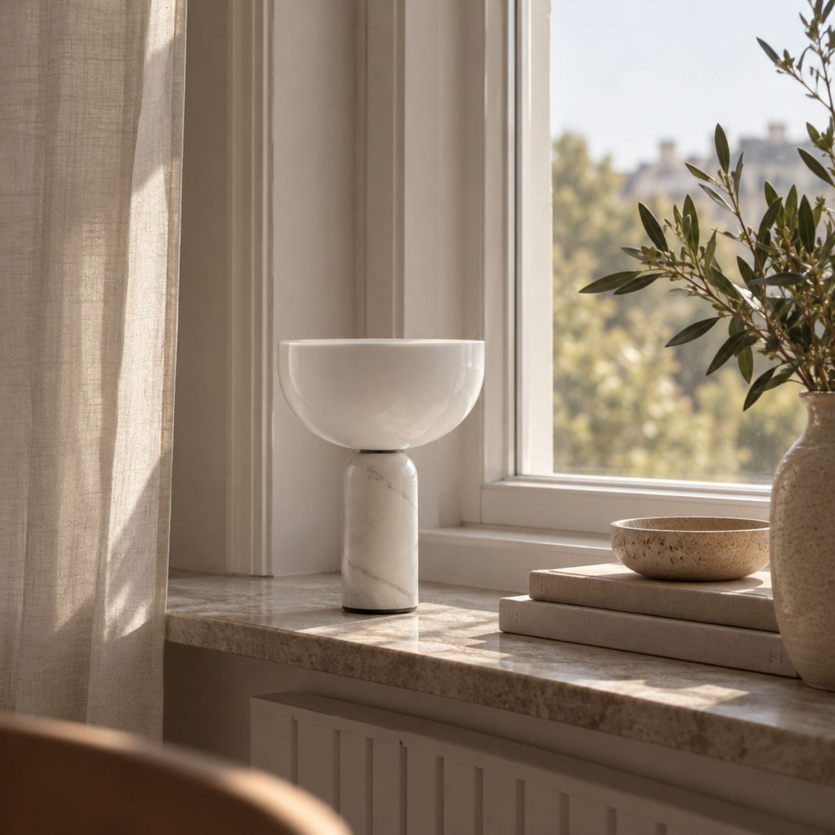 Bordslampa i vit marmor med vit skärm i naturligt fönsterljus.