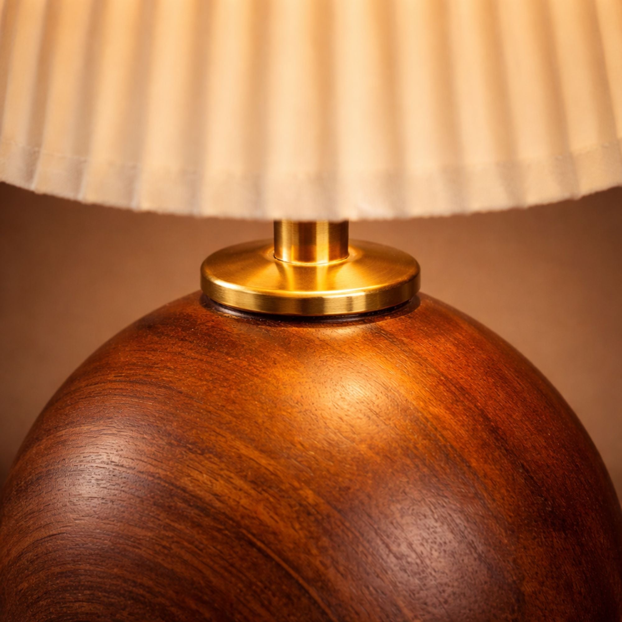 Närbild av bordslampa i mörk trä med guldfärgad detalj och plisserad lampskärm som visar hög kvalitet.