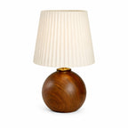 Bordslampa med mörk träfot och plisserad lampskärm i modern design på vit bakgrund.