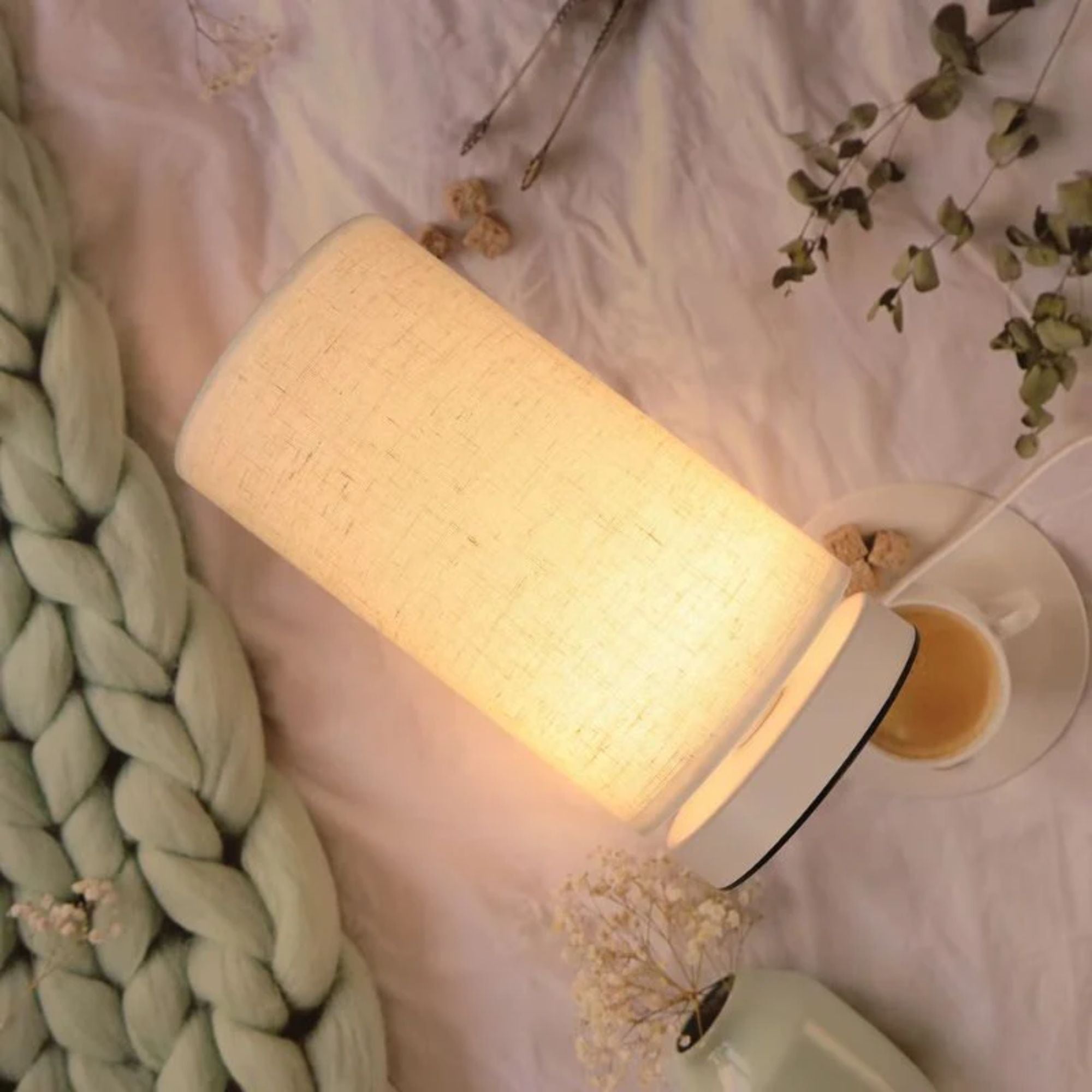 Bordslampa med mjuk textil som ger varm och mysig belysning i avslappnande sovrumsmiljö.
