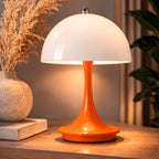Portabel orange LED bordslampa i svampdesign på träbord i modern interiör