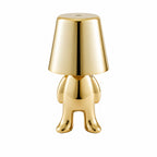 Uppladdningsbar bordslampa Buddy i guld med stående skulptural design.