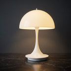 Portabel vit LED bordslampa i svampdesign som lyser med varm belysning mot mörk bakgrund