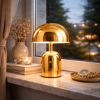 Portabel svamplampa i guld LED bordslampa vid fönster på kvällen med varm stämningsbelysning och elegant inredning