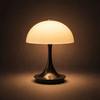 Portabel svart LED bordslampa i svampdesign som lyser med varm belysning mot mörk bakgrund