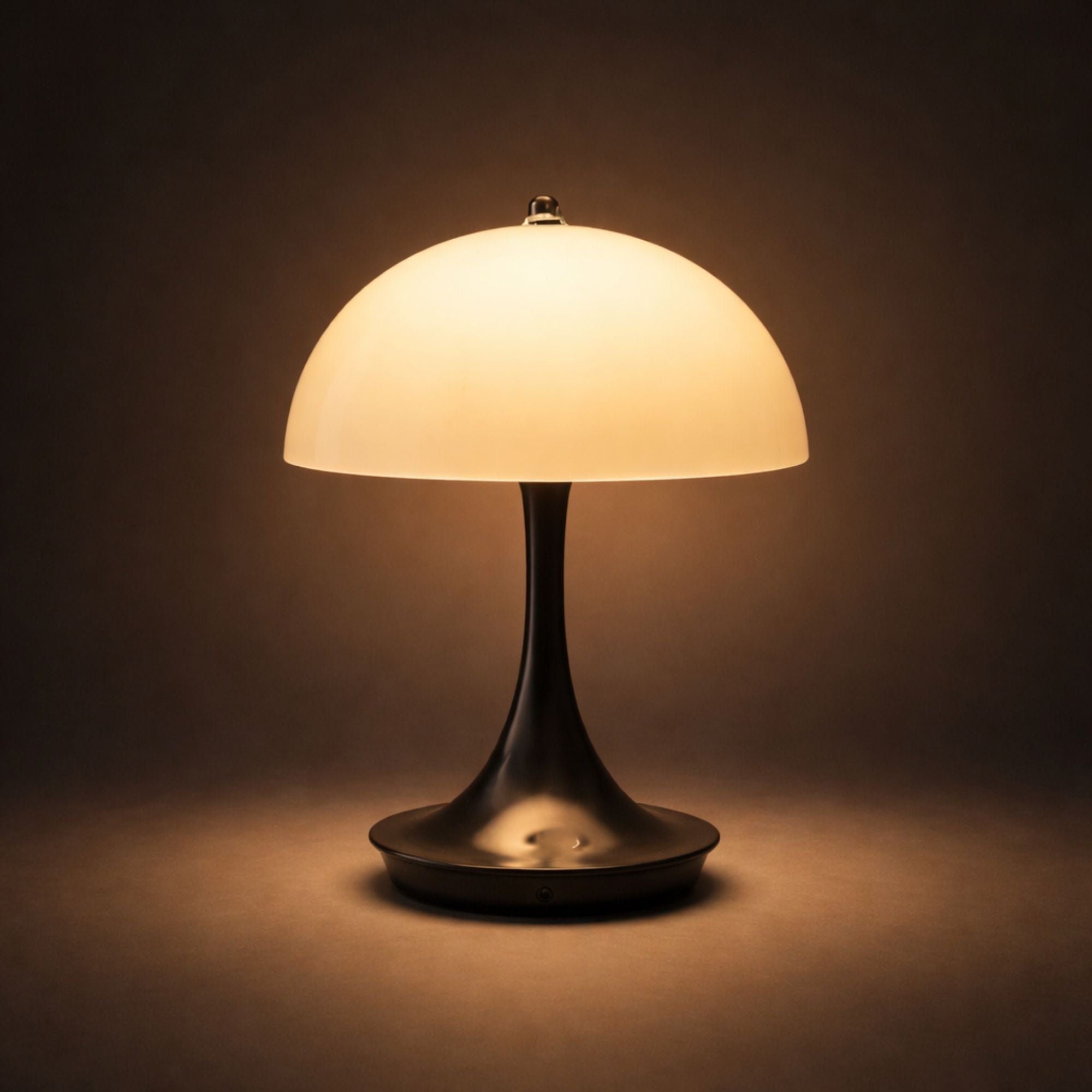 Portabel svart LED bordslampa i svampdesign som lyser med varm belysning mot mörk bakgrund