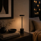 Svart uppladdningsbar LED-bordslampa i ett skandinaviskt vardagsrum med varm kvällsbelysning, böcker och modern minimalistisk inredning.