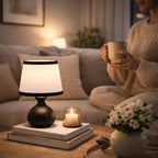 Elegant svart bordslampa med vit skärm som ger varm stämningsbelysning i mysigt vardagsrum