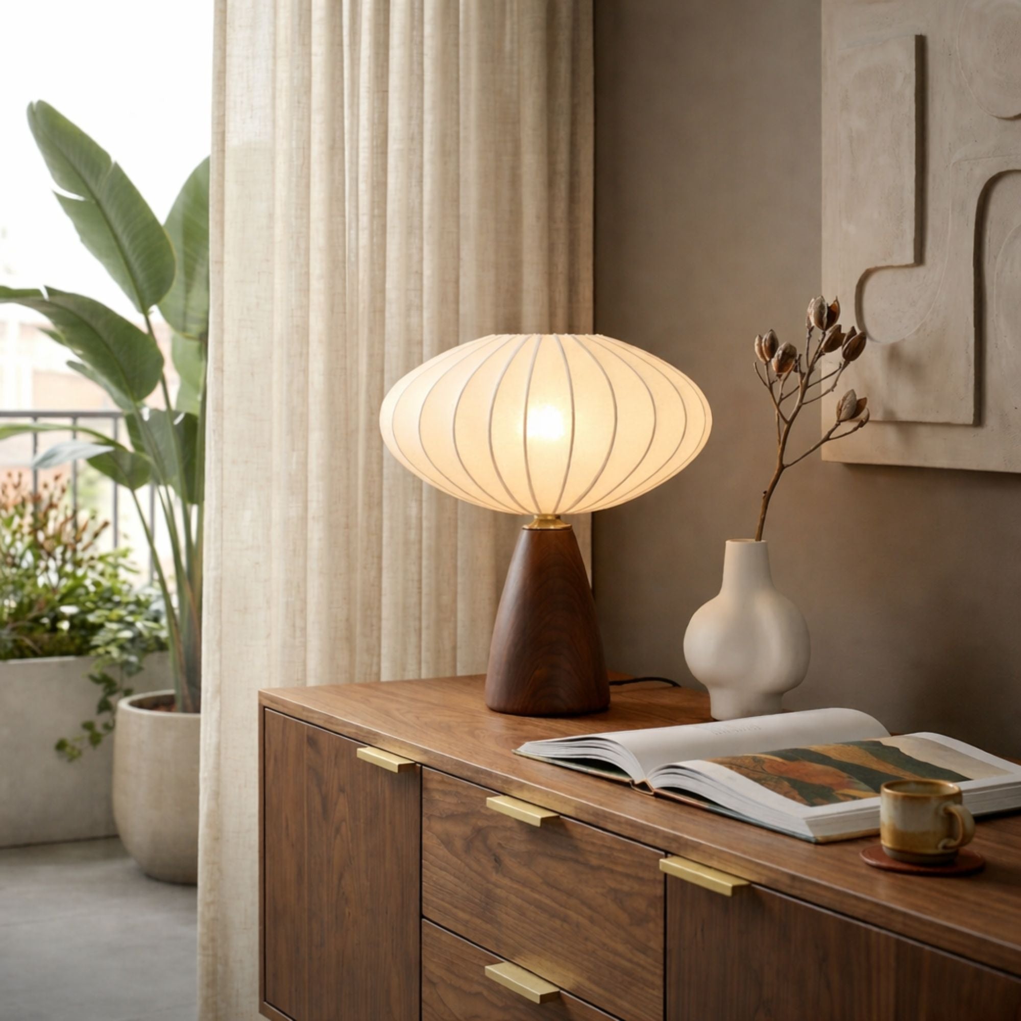 Skandinavisk bordslampa i trä med rund ballong skärm placerad på sideboard i vardagsrum med varm och mjuk belysning
