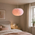Rosa fjäderlampa som skapar en varm och harmonisk känsla i ett modernt sovrum.