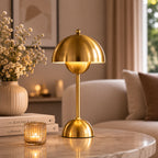 Portabel bordslampa i guld på soffbord i ett modernt skandinaviskt vardagsrum.