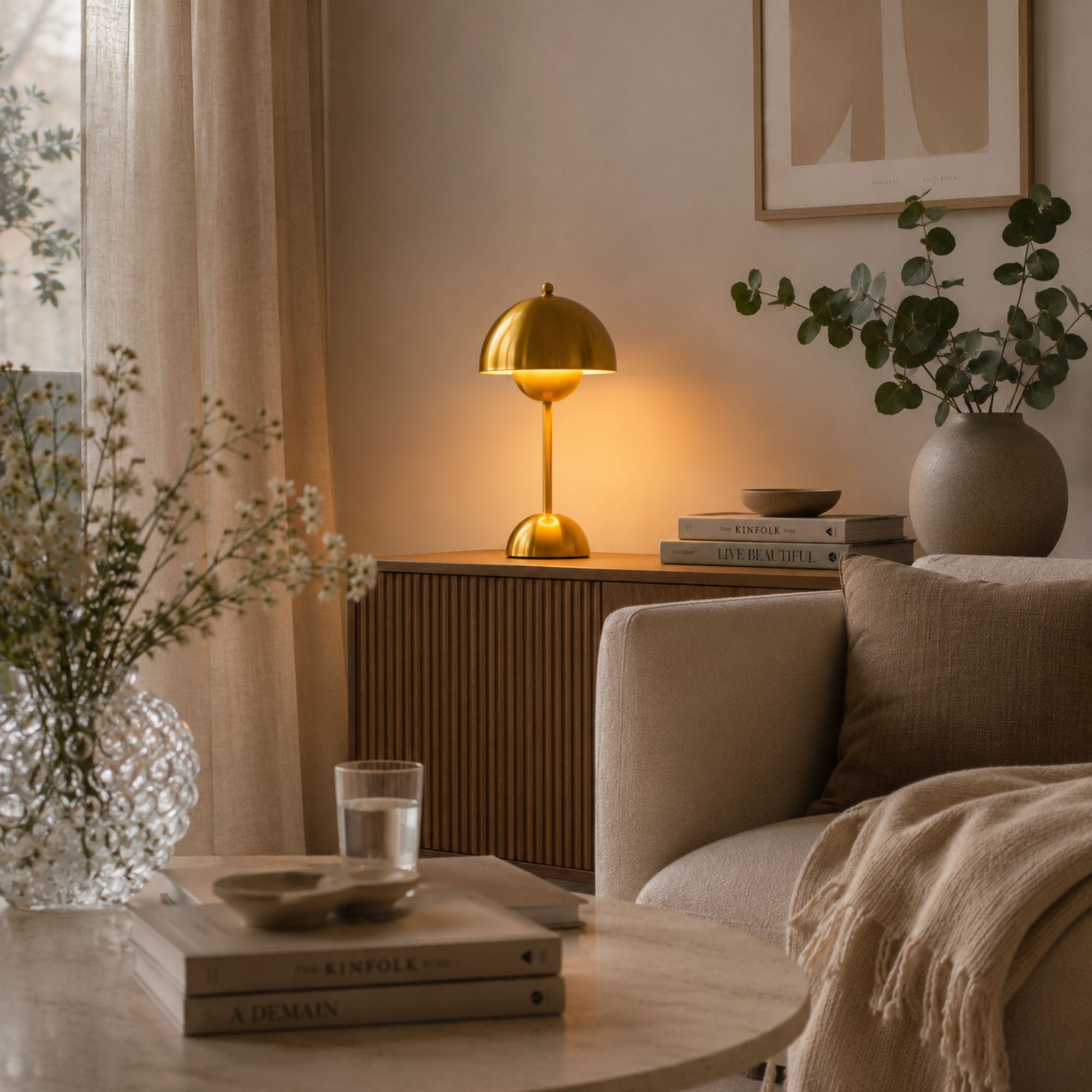 Portabel bordslampa i guld som skapar stämningsfull belysning i ett modernt svenskt vardagsrum.