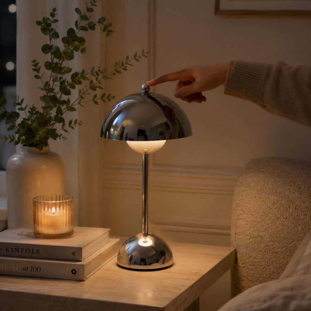 Hand som tänder Flowerbud bordslampa i krom med touchdimmer på ovansidan.