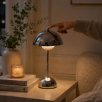 Hand som tänder Flowerbud bordslampa i krom med touchdimmer på ovansidan.