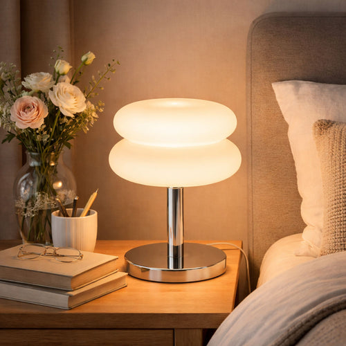 Modern bordslampa med opalglas och kromfot placerad på nattduksbord i mysigt sovrum
