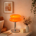 Orange retro bordslampa i glas med kromfot på sidobord i mysig pinterest-inspirerad inredning