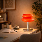 Retro röd bordslampa i glas med kromfot placerad på skrivbord i modern designhörna