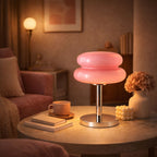 Rosa retro bordslampa i glas med kromfot som ger varm mysbelysning på sidobord i vardagsrum