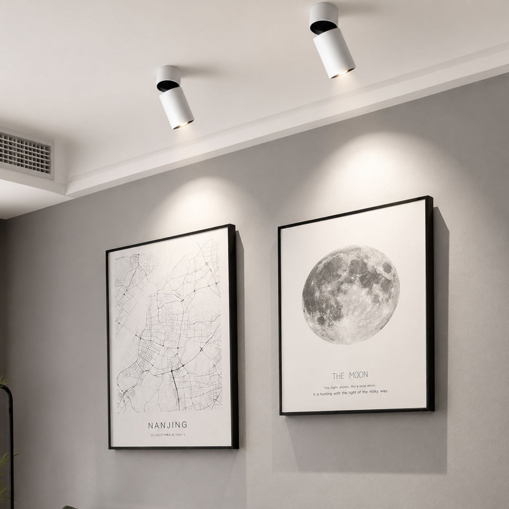 Vita LED-spotlights som belyser tavlor i ett modernt skandinaviskt vardagsrum.