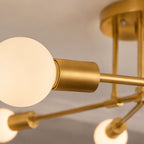 Taklampa detaljbild i close-up som visar borstad guldfärgad metall och vit glob i frostat glas med exklusiv modern design och varm belysning.