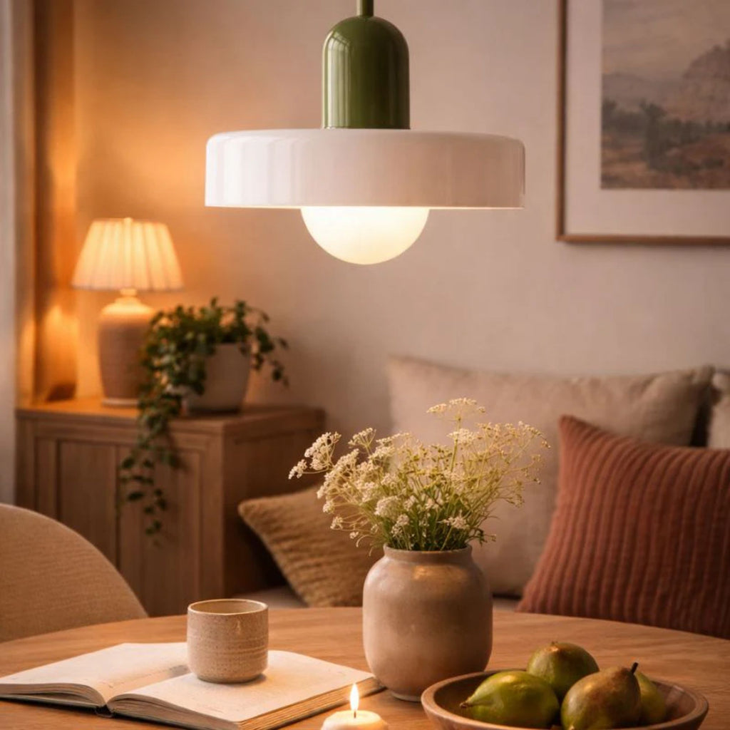 taklampa i grön och vit design som lyser över bord i mysigt vardagsrum med varm och stämningsfull belysning