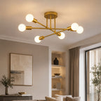 Taklampa i modern guldfärgad plafonddesign med 6 vita globlampor som skapar varm och exklusiv belysning i ett stilrent vardagsrum med elegant heminredning.