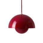 Röd pendellampa med rund metallskärm i modern skandinavisk design.