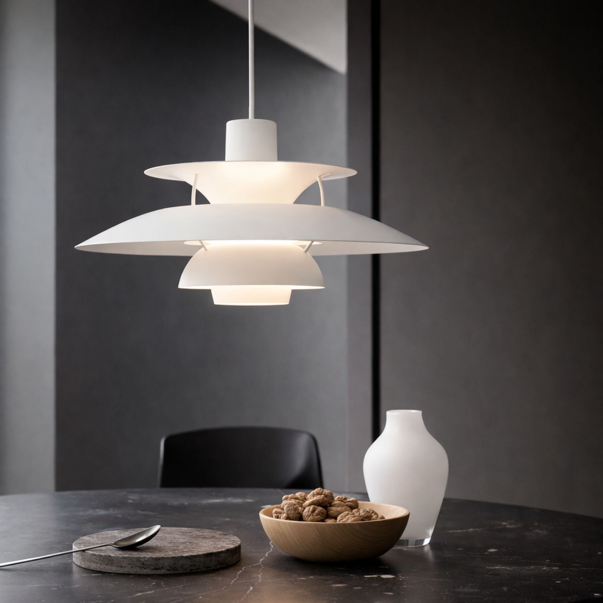 Taklampa pendellampa i metall med skandinavisk flerskärmsdesign som sprider varmt ljus över matbord på kvällen i köket.