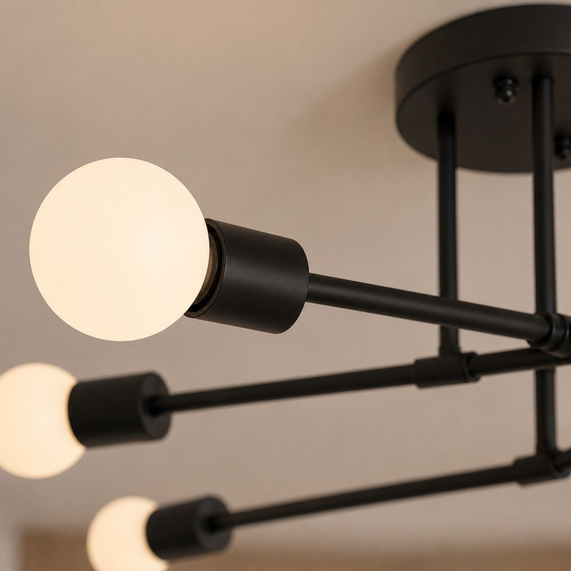 Taklampa detaljbild i close-up som visar svartlackerad metall och vit glob i frostat glas med modern minimalistisk design och exklusiv mjuk belysning.