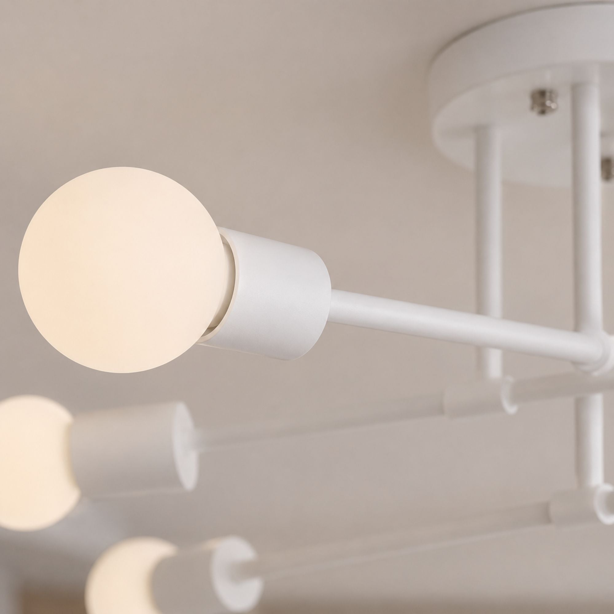Taklampa detaljbild i close-up som visar vitlackerad metall och vit glob i frostat glas med modern minimalistisk design och elegant mjuk belysning.