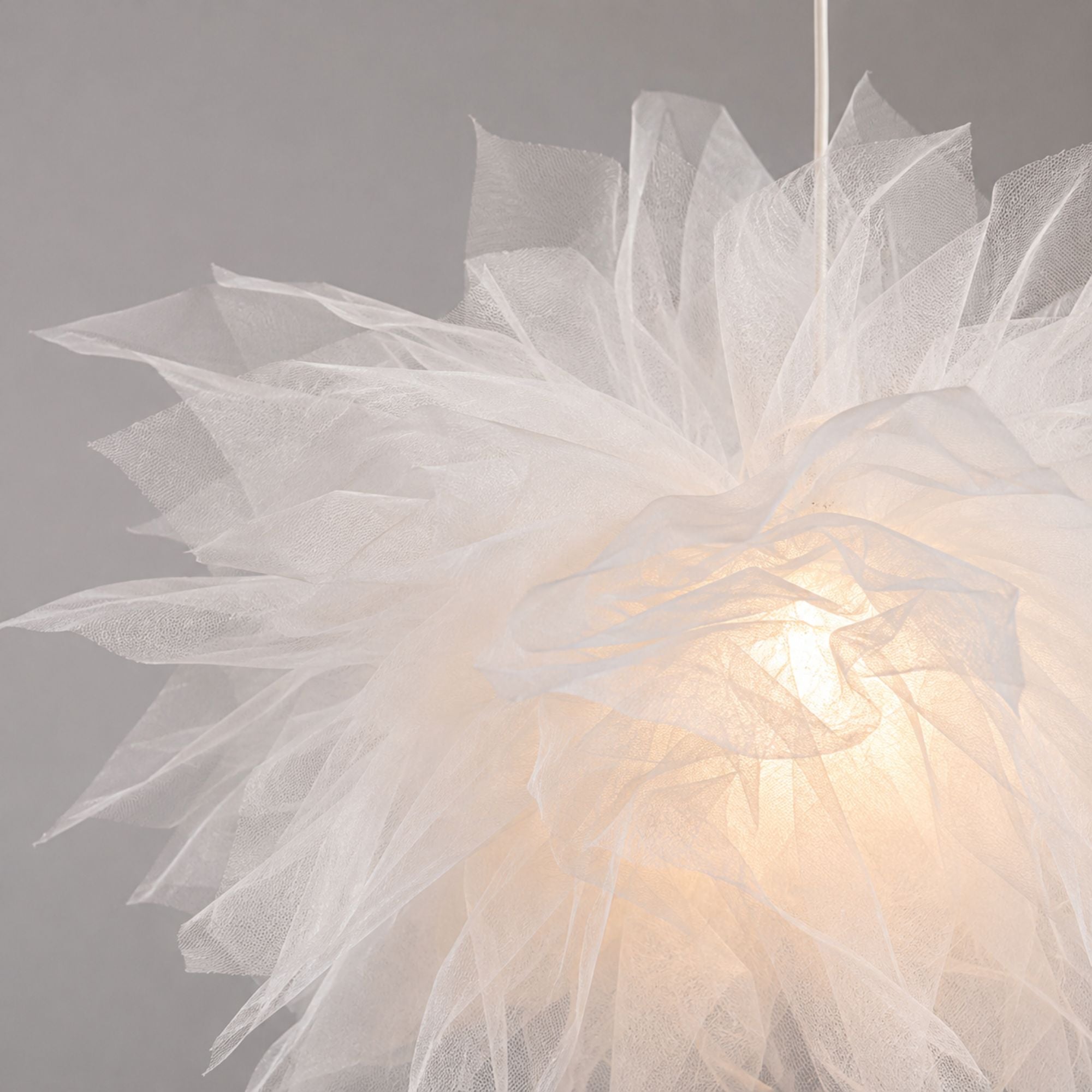Närbild av vit blomformad taklampa i mesh som visar de luftiga lagren och den eleganta texturen