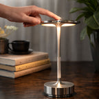 Hand som använder touchkontroll på uppladdningsbar LED bordslampa i metall med modern design