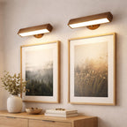 vägglampa i trä som tavelbelysning ovanför två tavlor i modern skandinavisk hall med varmt LED-ljus