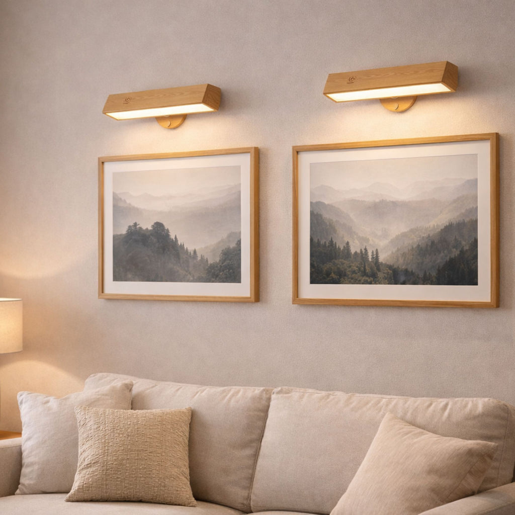 vägglampa i trä som tavelbelysning ovanför flera tavlor i modernt vardagsrum med varm LED-belysning